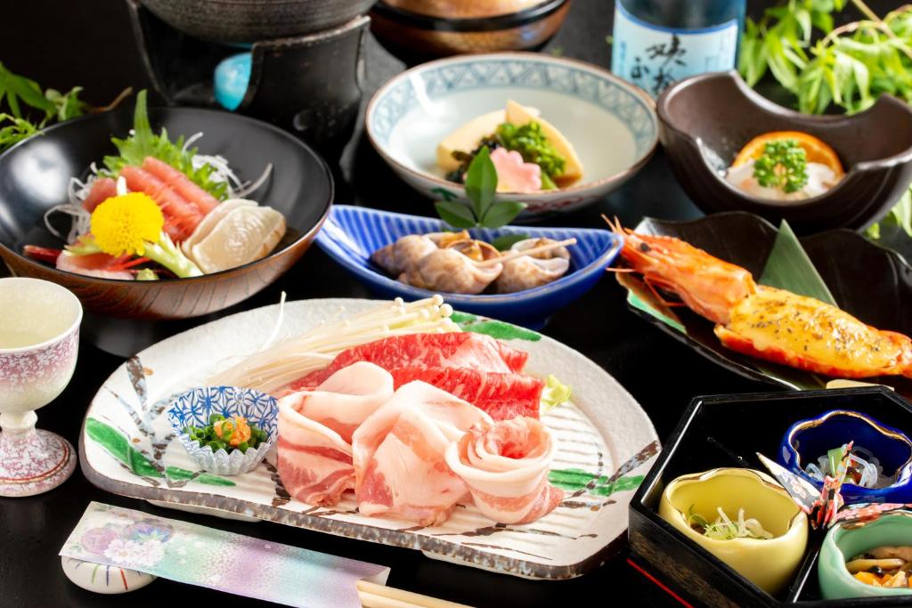 une table sur laquelle sont posés des bols contenant différents types d'aliments dans l'établissement ホテル晴山, à Chikuma