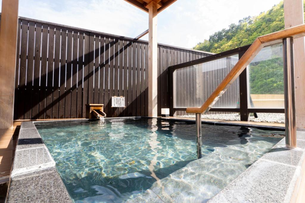une piscine intérieure avec une balustrade en bois et un escalier dans l'établissement ホテル晴山, à Chikuma