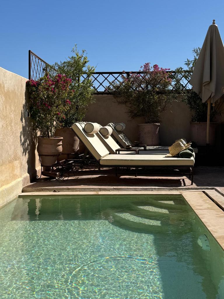 - une piscine avec un fauteuil et un parasol dans l'établissement Riad Abracadabra, à Marrakech