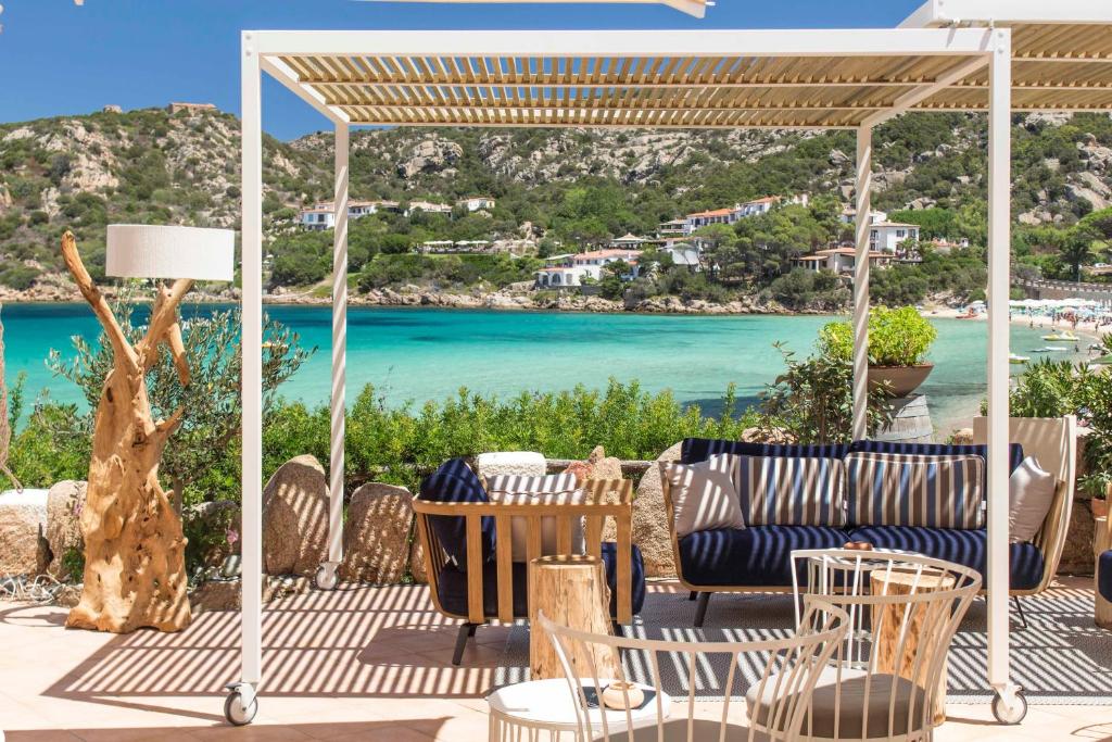 un patio avec une table et des chaises et une vue sur l'océan dans l'établissement Club Hotel Baja Sardinia, à Baja Sardinia