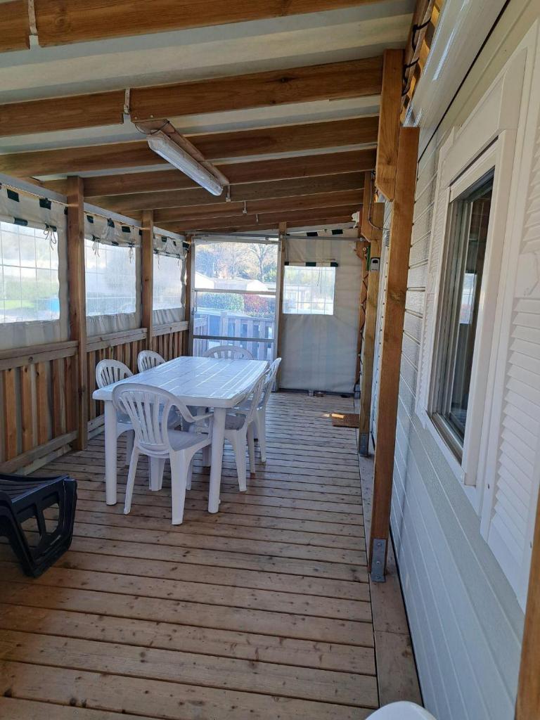 une terrasse en bois avec une table et des chaises dessus dans l'établissement mobil home 3 chambres 2 sdb 750, à Pont-Aven