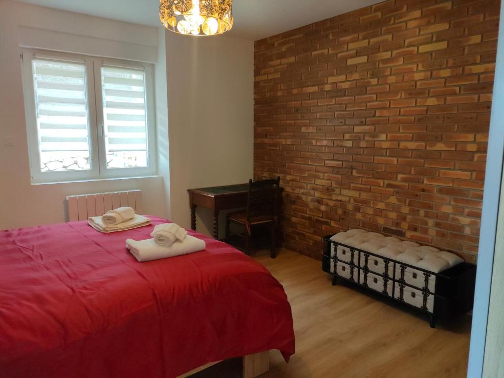- une chambre avec un lit rouge et un mur en briques dans l'établissement bel appartement 3 pièces dans la Résidence Vosges-Alsace Orbey, à Orbey