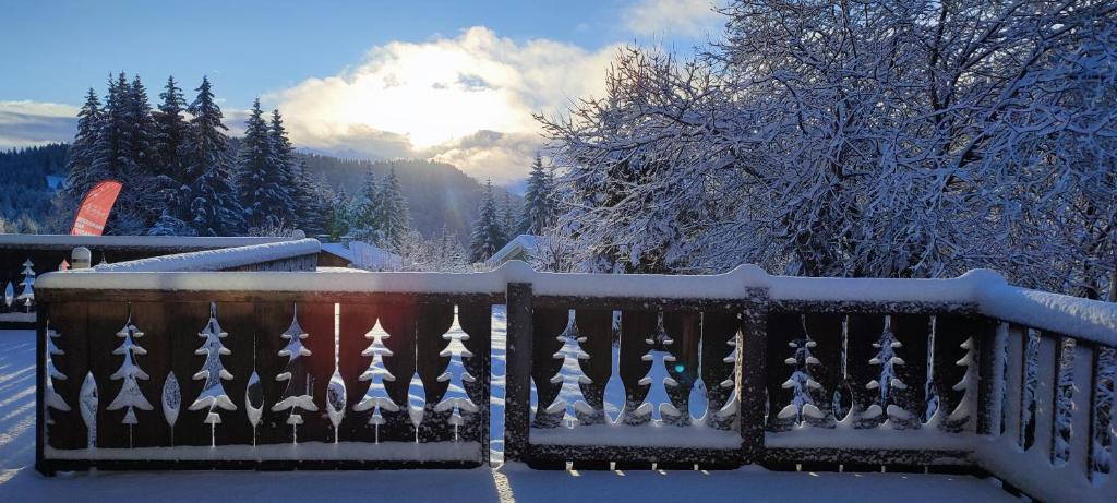 une clôture recouverte de neige avec le soleil en arrière-plan dans l'établissement Le Taconet, à Praz de Lys - Sommand