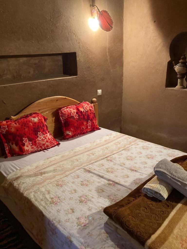 une chambre avec un grand lit avec des oreillers rouges dans l'établissement Authentic riad & activities Erg, à M'Hamid El Ghizlane