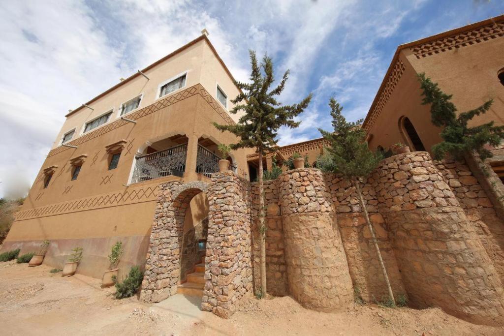 une grande maison avec un mur de pierre devant elle dans l'établissement Riad Villa Dades, à Boumalne