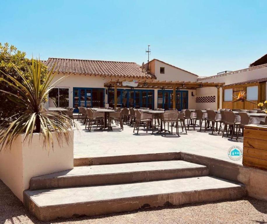 un patio avec tables et chaises dans un bâtiment dans l'établissement SOLEIL & PLAGE au CAMPING MAR ESTANG 4 ETOILES 3 chambres 2 salle de bain, à Canet