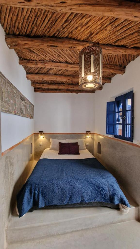 une chambre avec un grand lit avec une couverture bleue dans l'établissement DAR DAREK FAMILY, à Essaouira