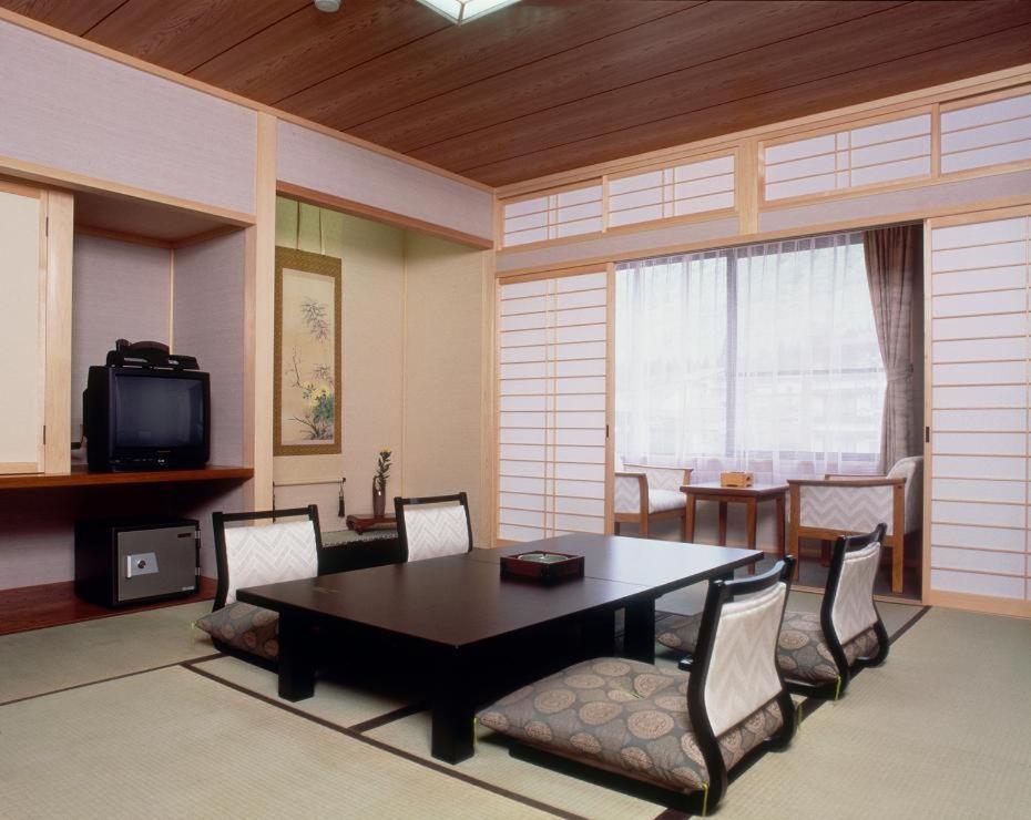 une pièce avec une table, des chaises et une télévision dans l'établissement Hiratakan, à Takayama