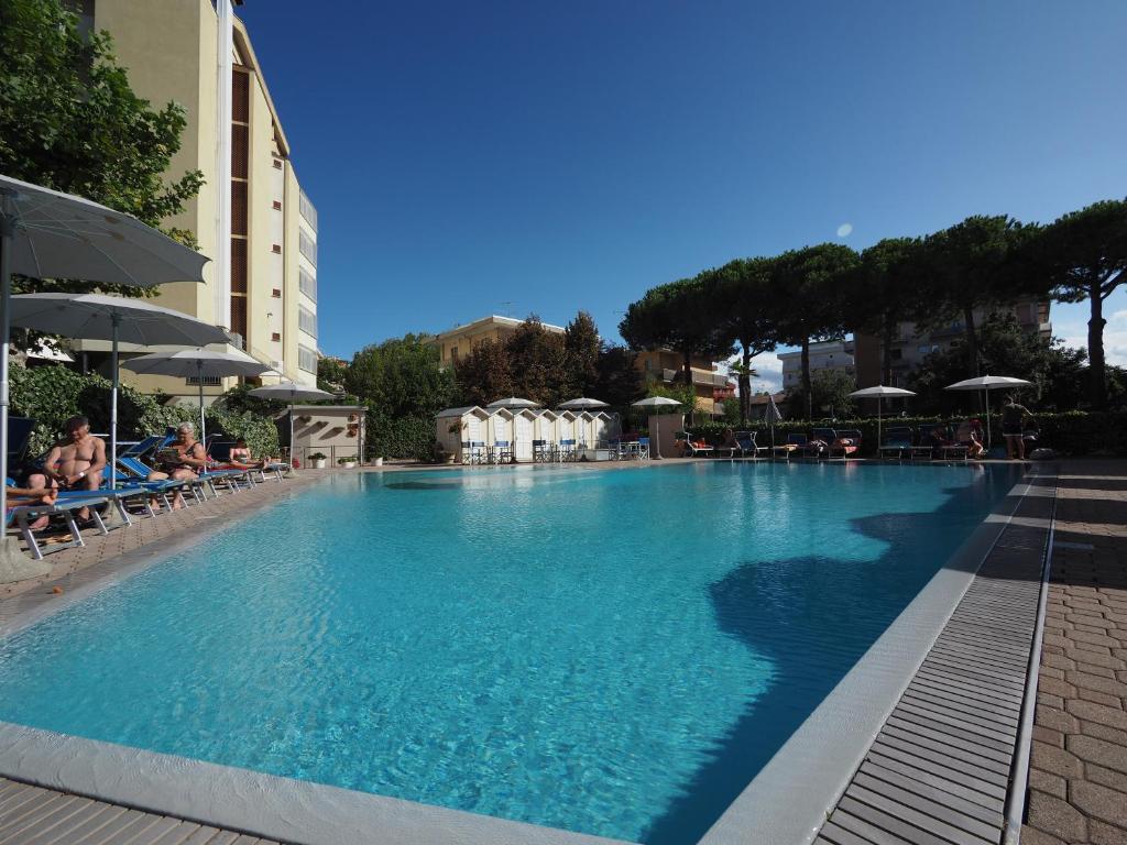 une grande piscine avec chaises et parasols dans l'établissement Hotel Colorado Cesenatico, à Cesenatico