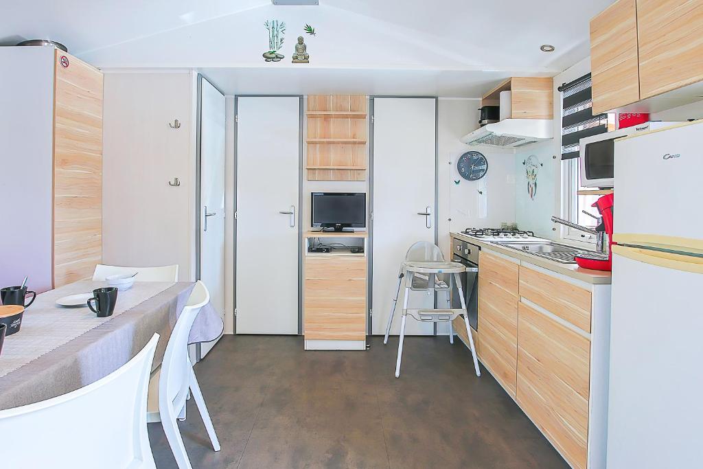 une cuisine avec des armoires en bois et une table à l'intérieur dans l'établissement New - Mobil home tout équipé, à Saint-Jean-de-Monts