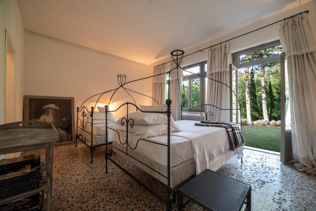 - une chambre avec un lit en métal et une fenêtre dans l'établissement La Scuola, Luxueuse villa avec piscine privée, à San Casciano dei Bagni