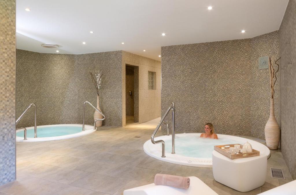 une femme dans une baignoire dans une salle de bains dans l'établissement Résidence Club mmv Le Hameau des Airelles ****, à Montgenèvre