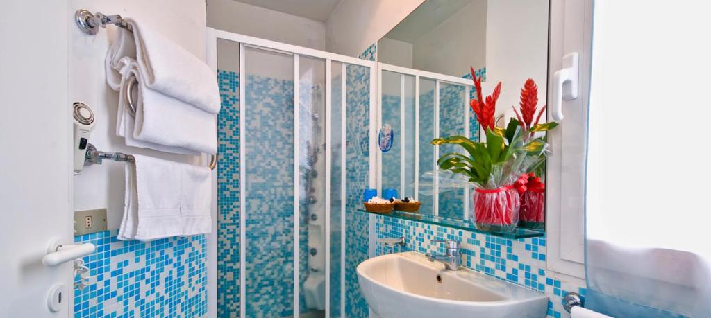 La salle de bains est pourvue de carrelage bleu, d'un lavabo et d'un miroir. dans l'établissement Hotel Sirius Riccione, à Riccione