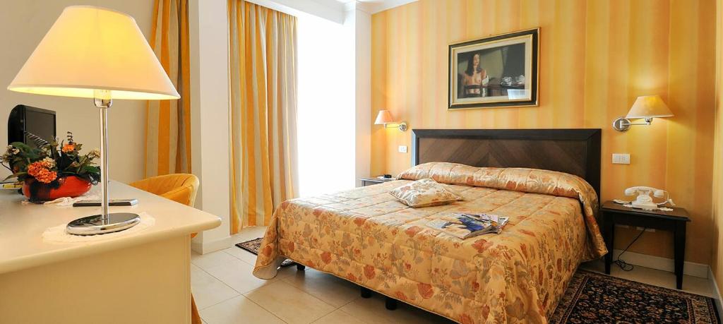 une chambre d'hôtel avec un lit, une table et une lampe dans l'établissement Hotel Sirius Riccione, à Riccione
