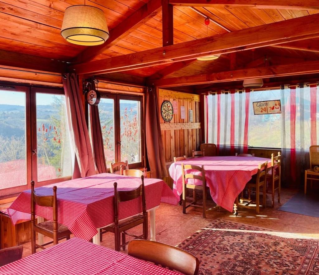 - une salle à manger avec 2 tables, des chaises et des fenêtres dans l'établissement Anouchka Ô fil 2 l'eau, yourte en bord de Lac, à Saint-Maurice-sur-Loire