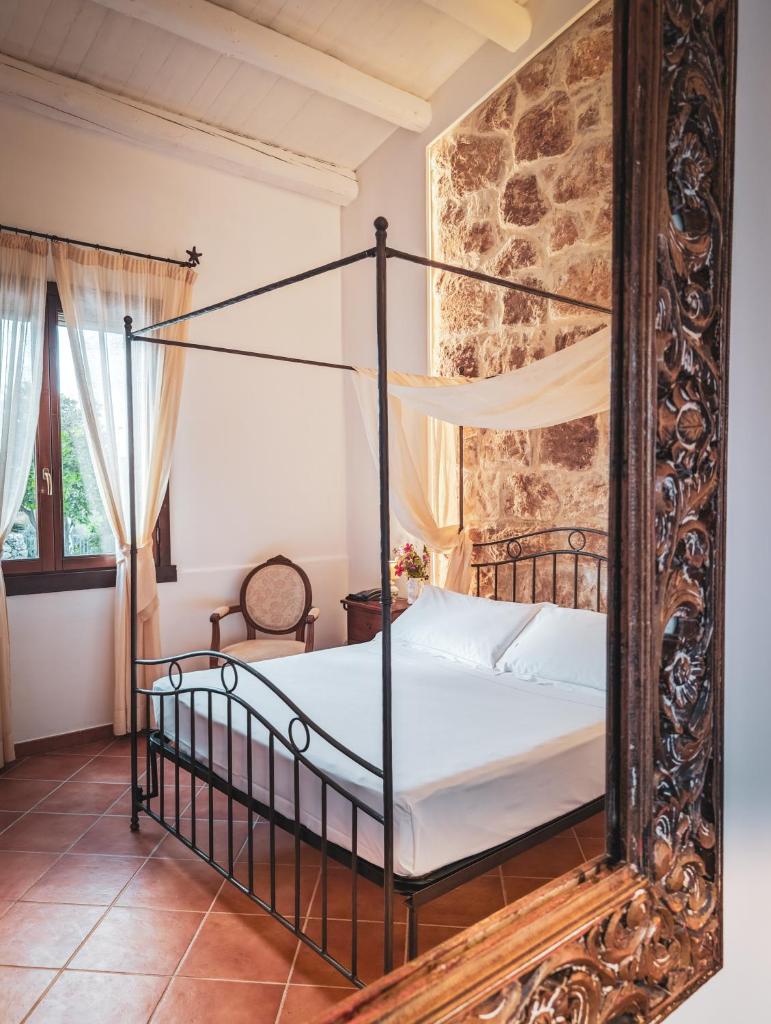 une chambre avec un lit à baldaquin avec un miroir dans l'établissement Hotel La Corte Del Sole, à Noto