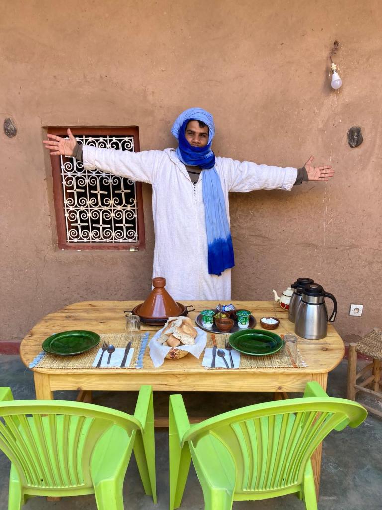 Un homme se tient devant une table dans l'établissement Authentic riad & activities Erg, à M'Hamid El Ghizlane