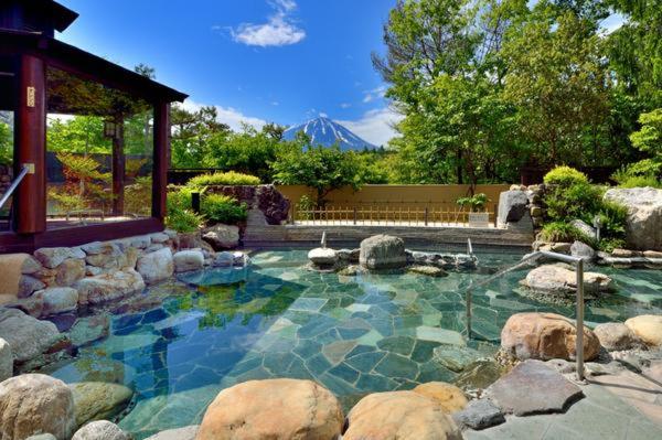 - une grande piscine avec des rochers dans une cour dans l'établissement Fujimien, à Fujikawaguchiko