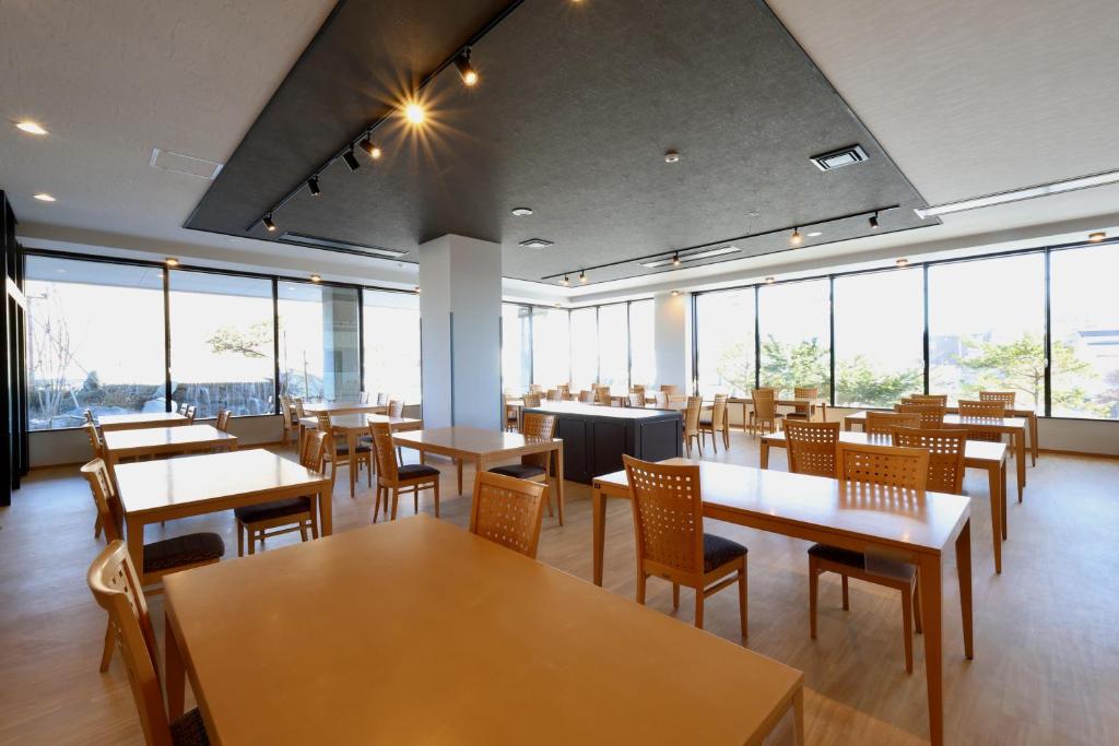 un restaurant avec des tables, des chaises et des fenêtres dans l'établissement Kojohama Onsen Hotel, à Shiraoi