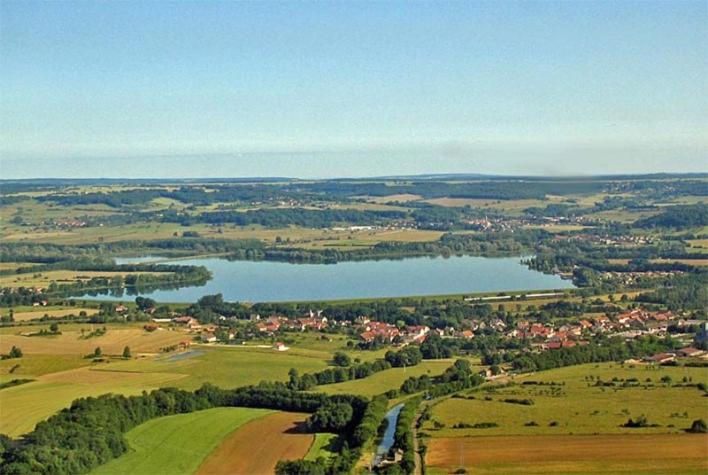 une vue aérienne sur un lac dans un champ dans l'établissement Camping du Lac, à Villegusien Le Lac