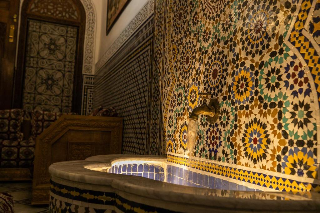une fontaine dans une pièce dotée d'un mur en mosaïque dans l'établissement Riad Jamal, à Fès