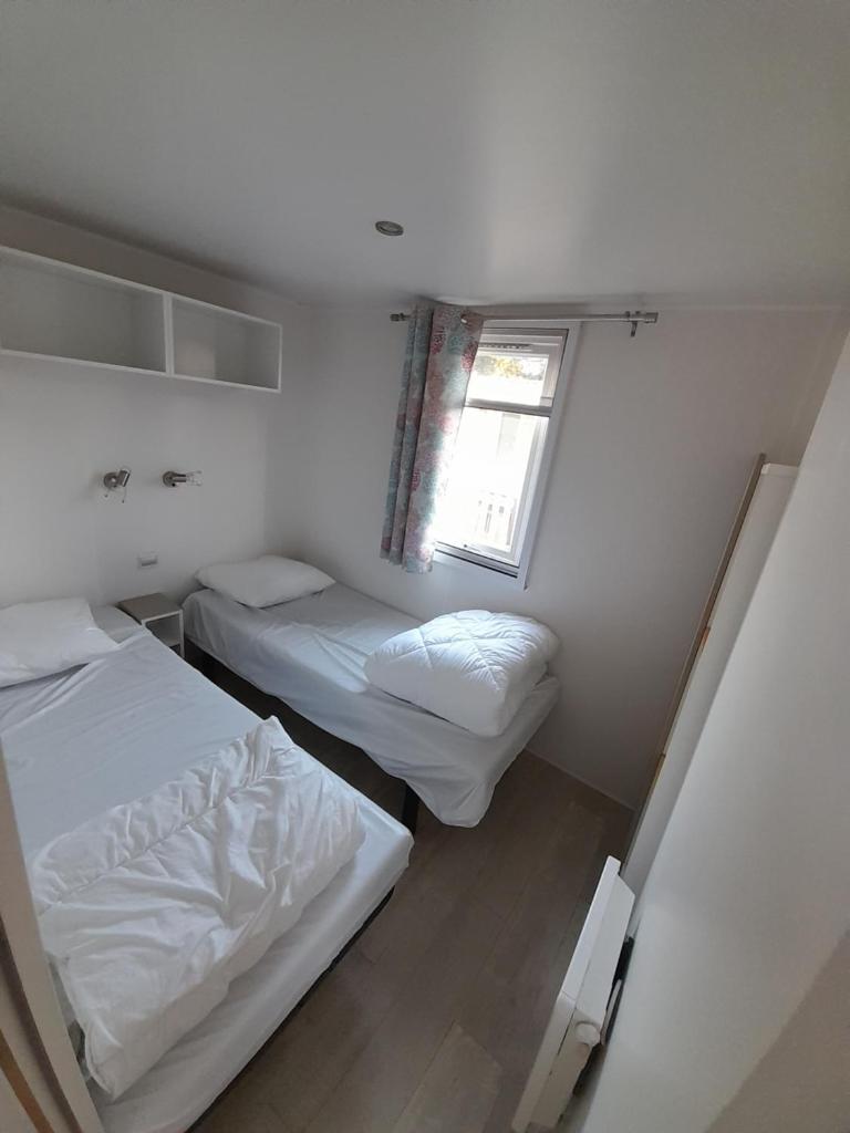 une petite chambre avec deux lits et une fenêtre dans l'établissement mobil-home philvar, à Douarnenez 25 autres photos