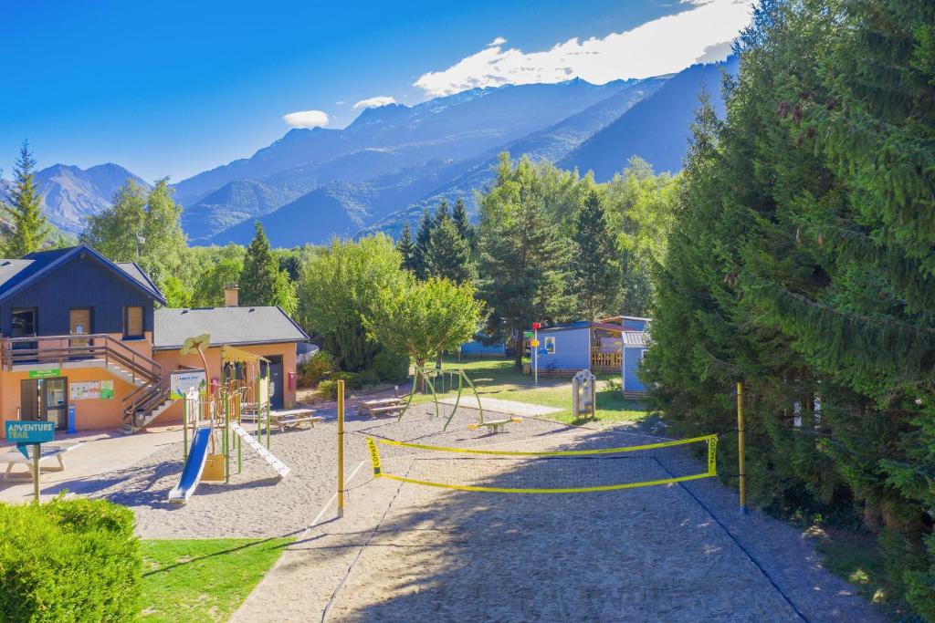 un parc avec une aire de jeux avec des montagnes en arrière-plan dans l'établissement Camping RCN Belledonne, au Bourg-dʼOisans