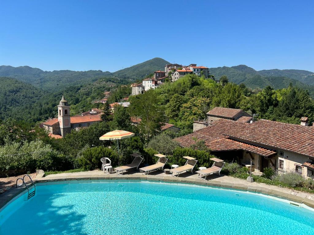 une piscine avec des chaises et un parasol dans l'établissement Podere Beatrice 20 Pax by VILLASRETREATS, à Bardine di San Terenzo Monti
