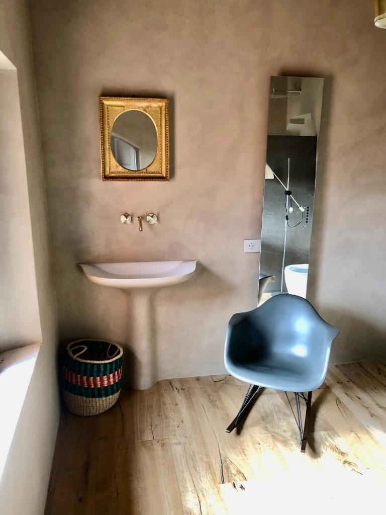 La salle de bains est pourvue d'un lavabo et d'une chaise bleue. dans l'établissement Casagatti villa di lusso, à Fungaia