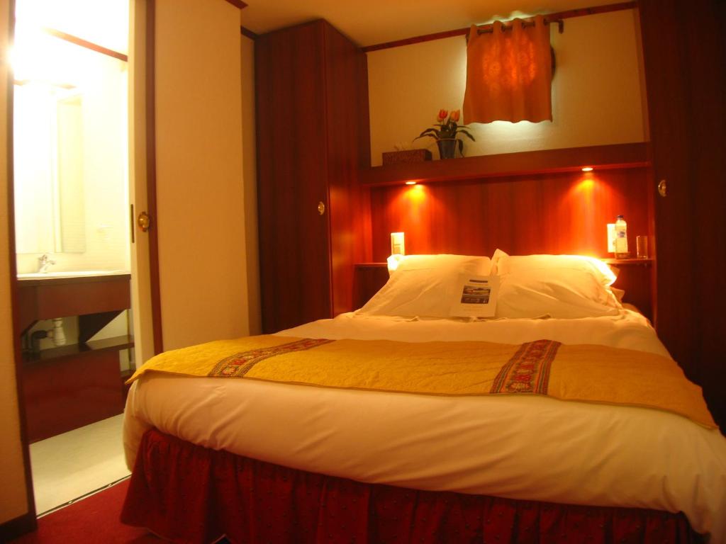 une chambre avec un grand lit avec une tête de lit rouge dans l'établissement Bateau Le Phénicien, à Aigues-Mortes 2 autres photos