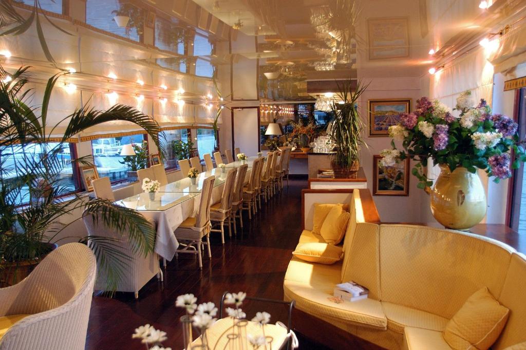 un restaurant avec des tables blanches, des chaises et des fleurs dans l'établissement Bateau Le Phénicien, à Aigues-Mortes