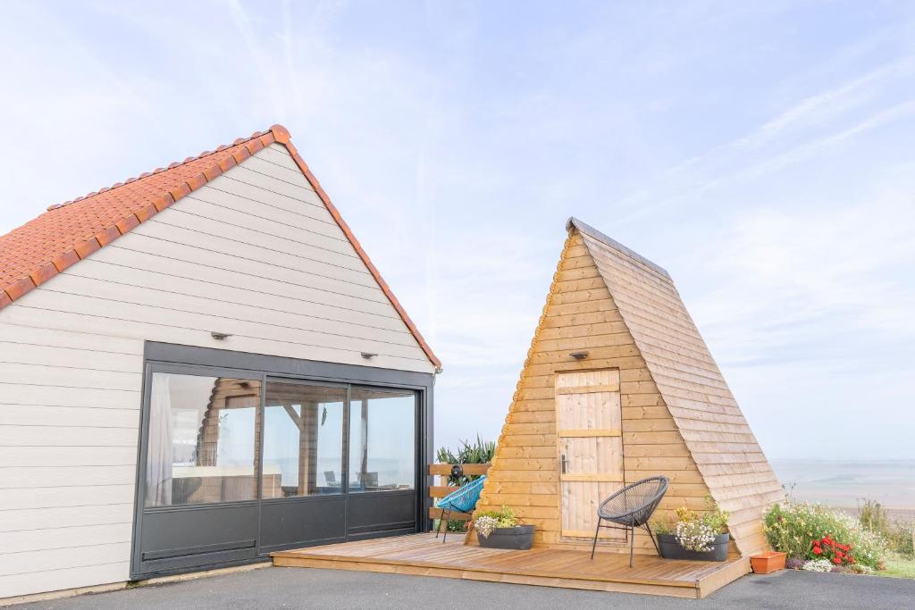 une petite maison avec une grande fenêtre sur une terrasse dans l'établissement Nuit insolite à la campagne, à Fiennes