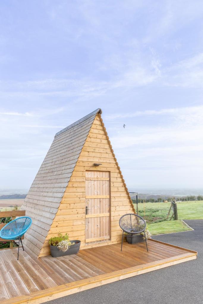 une petite maison avec un toit sur une terrasse en bois dans l'établissement Nuit insolite à la campagne, à Fiennes