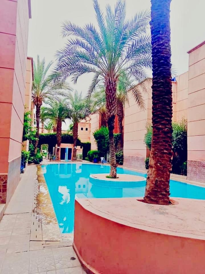 une piscine avec des palmiers devant un immeuble dans l'établissement Riad DarDamia, à Marrakech 14 autres photos