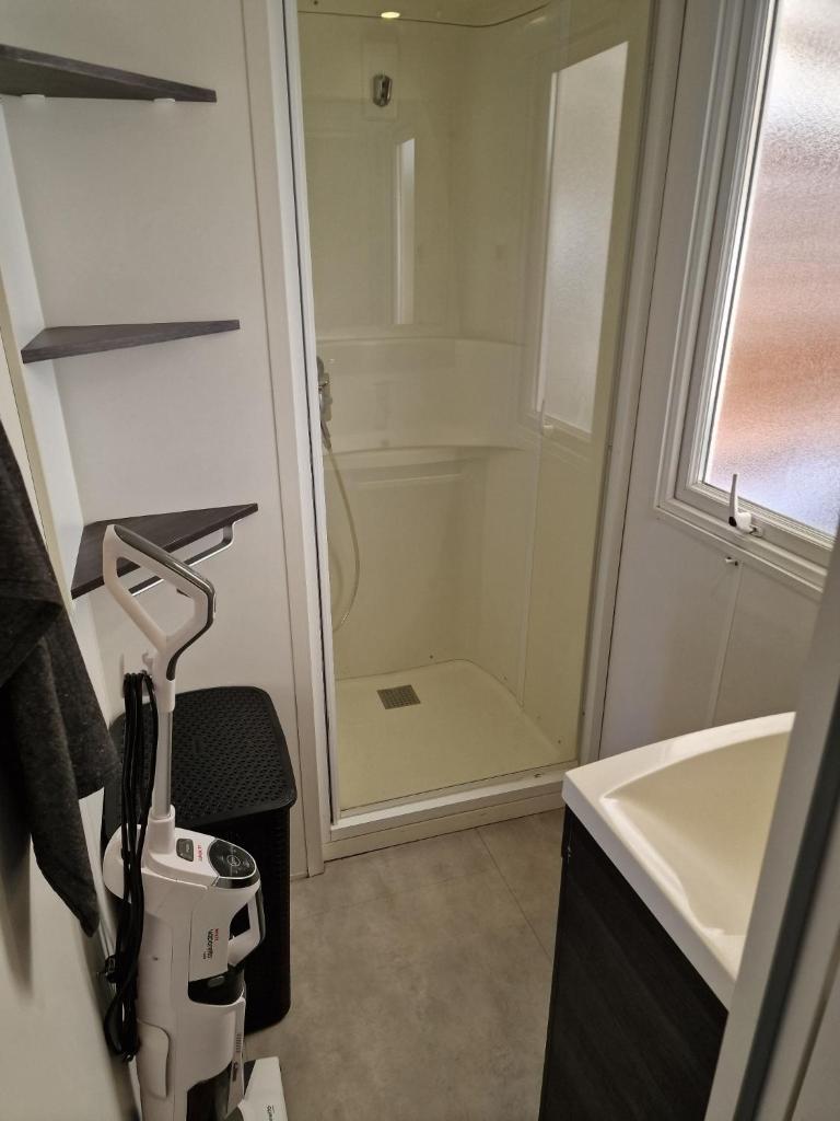 une salle de bain avec une douche, un lavabo et un miroir dans l'établissement Camping Carabasse Vias plage., à Vias