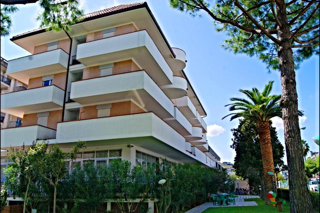 un grand bâtiment avec des arbres devant lui dans l'établissement Hotel Blumen, à San Benedetto del Tronto