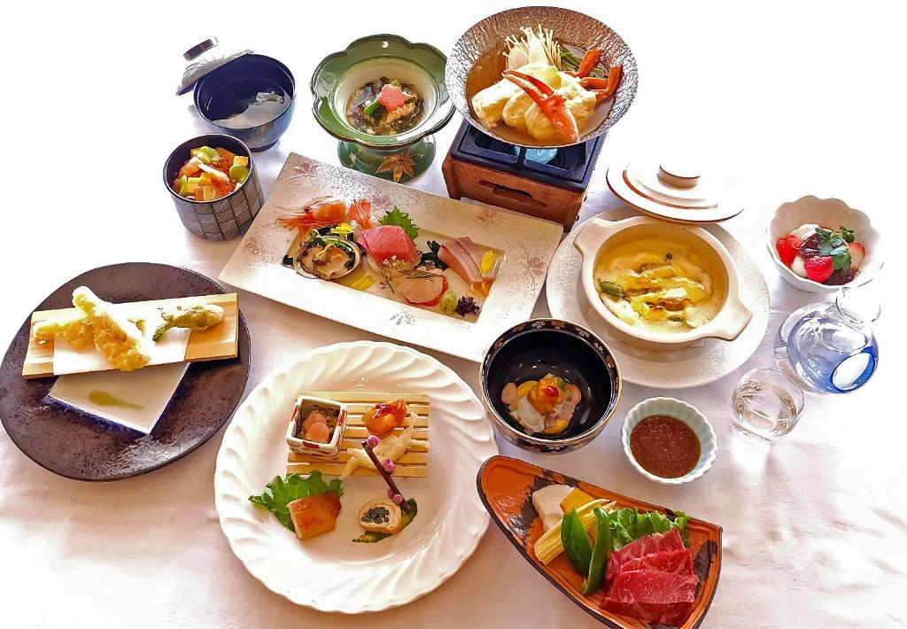 une table avec des assiettes et des bols de nourriture dans l'établissement Yunohama Hotel, à Hakodate