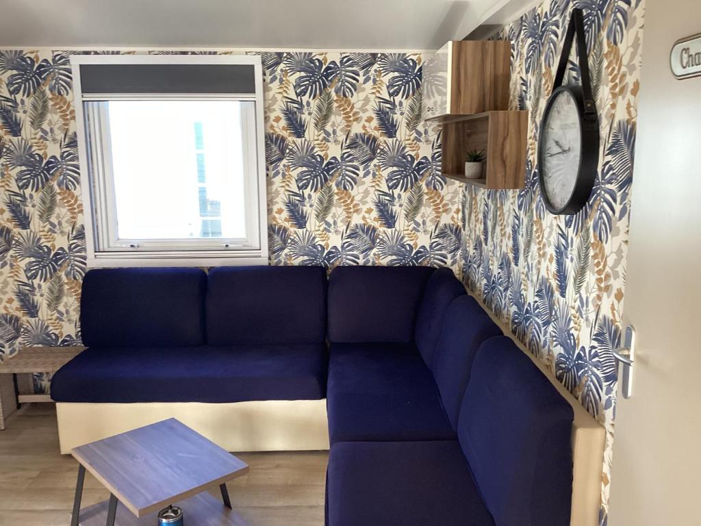 un salon avec un canapé bleu et une fenêtre dans l'établissement Frejus tout confort, climatisation,plus ventilation toutes les chambres, linge de lit et de toilette , coffre fort, lavé vaisselle machine à laver grande terrasse couverte velos et wifi possible, à Fréjus
