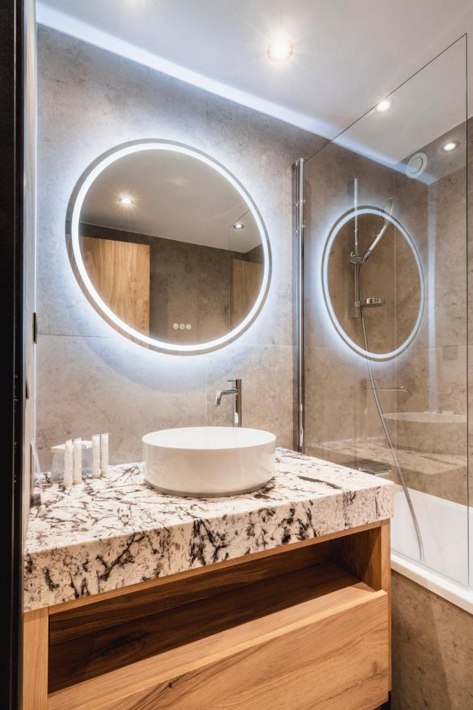 une salle de bain avec un lavabo et un miroir dans l'établissement Hotel Les Mélèzes, à Les Deux Alpes 35 autres photos