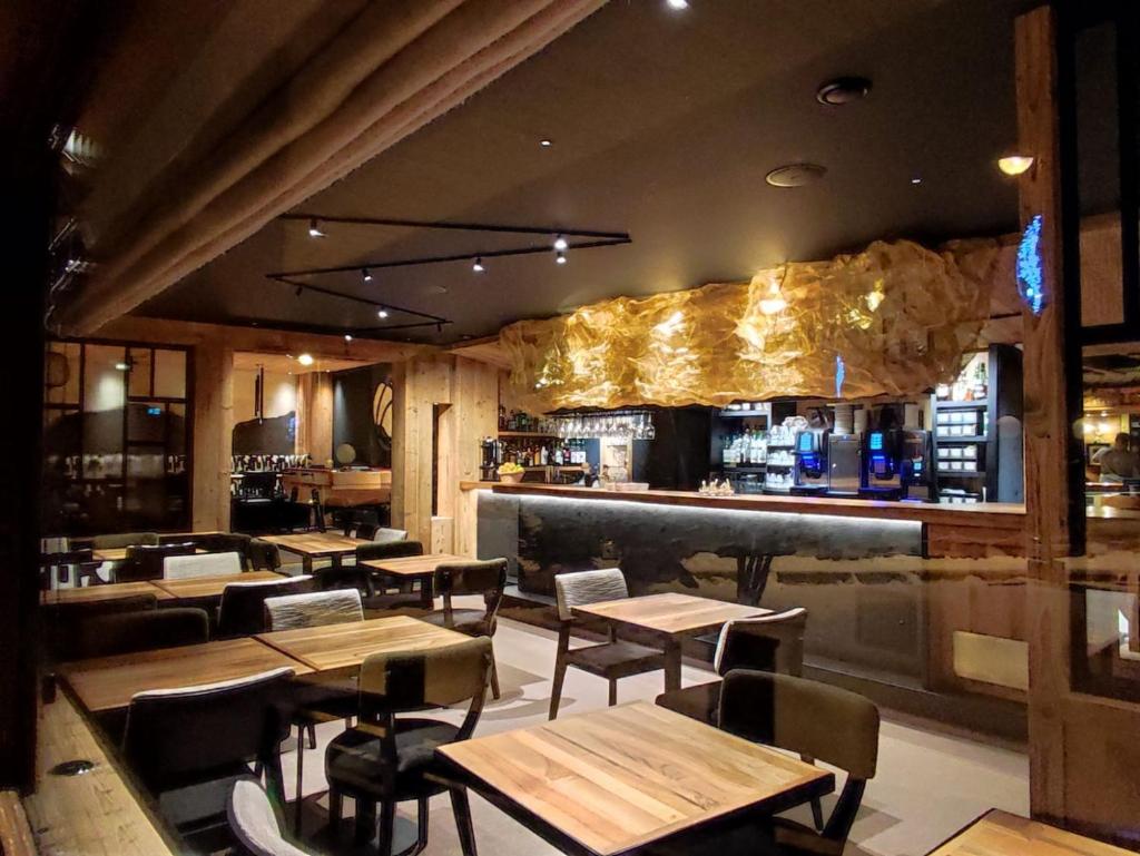un restaurant avec des tables et des chaises en bois ainsi qu'un bar dans l'établissement Hotel Les Mélèzes, à Les Deux Alpes