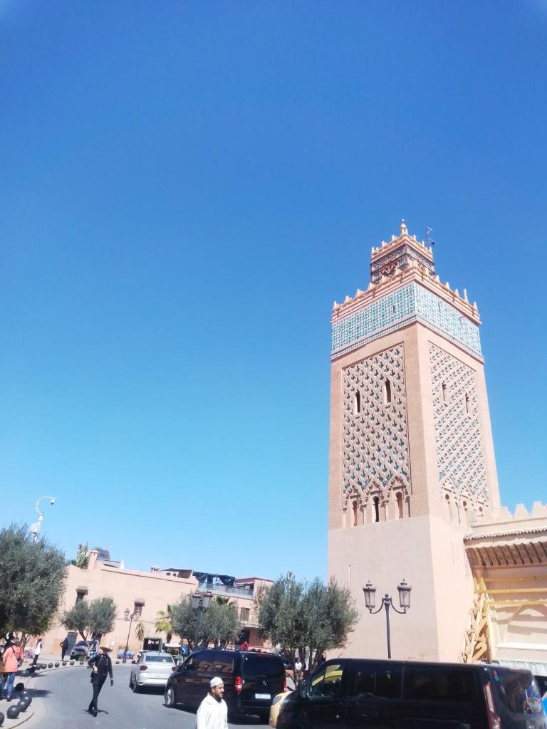 une tour d'horloge dans une ville avec des voitures garées dans l'établissement Riad Bouganville Bleu, à Marrakech 37 autres photos