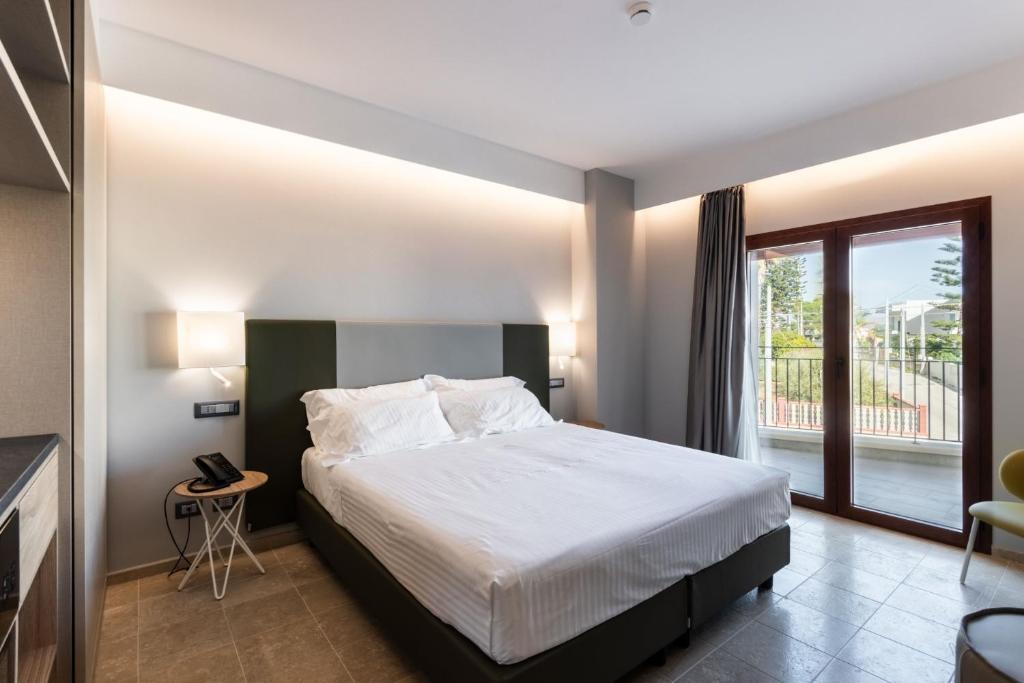 une chambre avec un lit et une grande fenêtre dans l'établissement Hotel Netum Mare, à Noto Marina