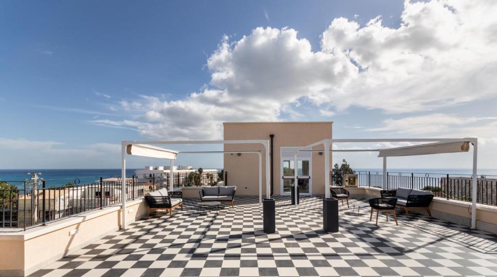 un patio avec des chaises et un sol en damier dans l'établissement Hotel Netum Mare, à Noto Marina