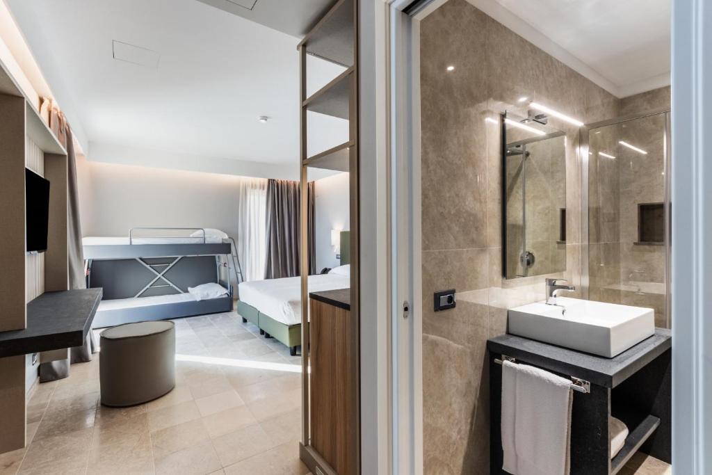 une salle de bain avec un lavabo et une salle de bain avec un lit dans l'établissement Hotel Netum Mare, à Noto Marina