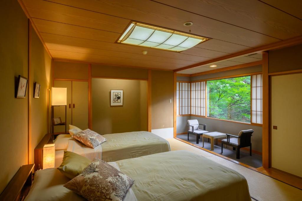 une chambre avec deux lits, un bureau et une fenêtre dans l'établissement Senkeien Tsukioka Hotel, à Kaminoyama