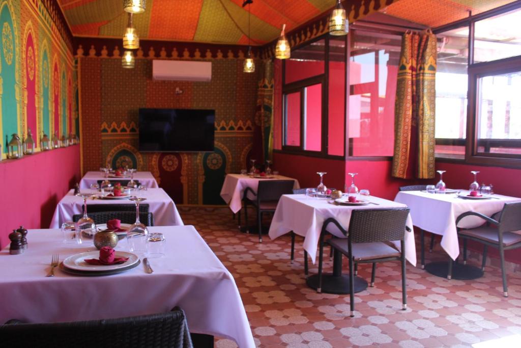 un restaurant avec des tables et des chaises blanches et des murs roses dans l'établissement Riad Hilmuna Hammam et Spa, à Marrakech