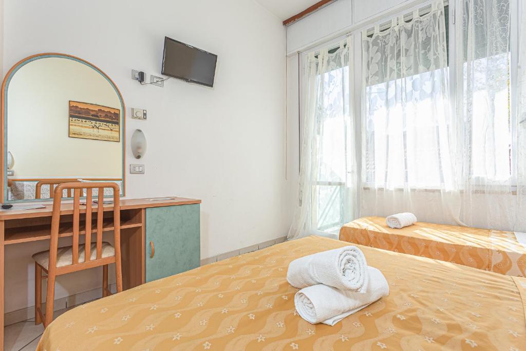 une chambre avec deux lits, un bureau et un miroir dans l'établissement Hotel Gadames - Lunch on the Beach, à Cervia