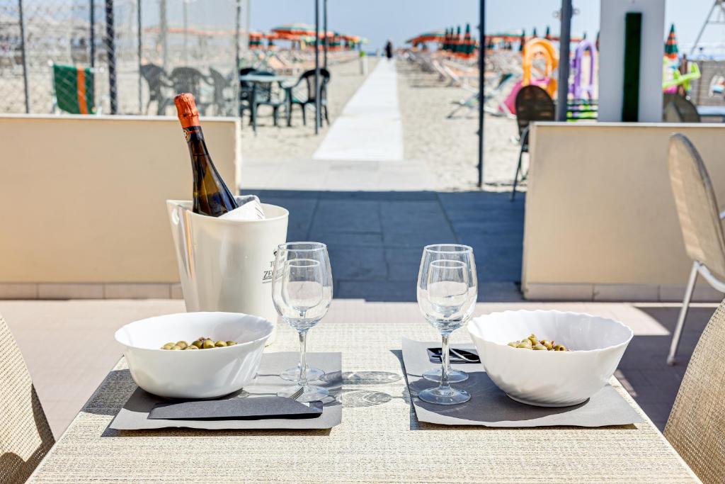 - une table avec 2 bols blancs et des verres à vin dans l'établissement Hotel Gadames - Lunch on the Beach, à Cervia