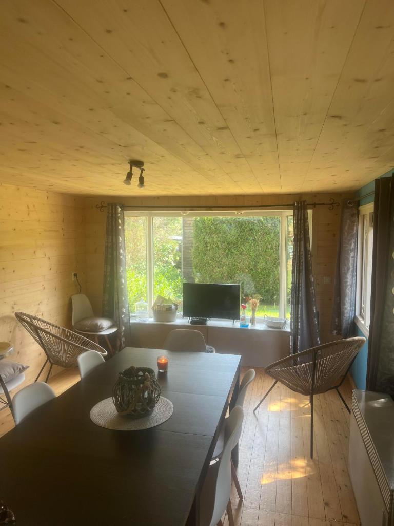 une pièce avec une table, des chaises et une télévision dans l'établissement Chalet 9 personnes, piscine, terrasse, à Saint-Maurice-sur-Moselle
