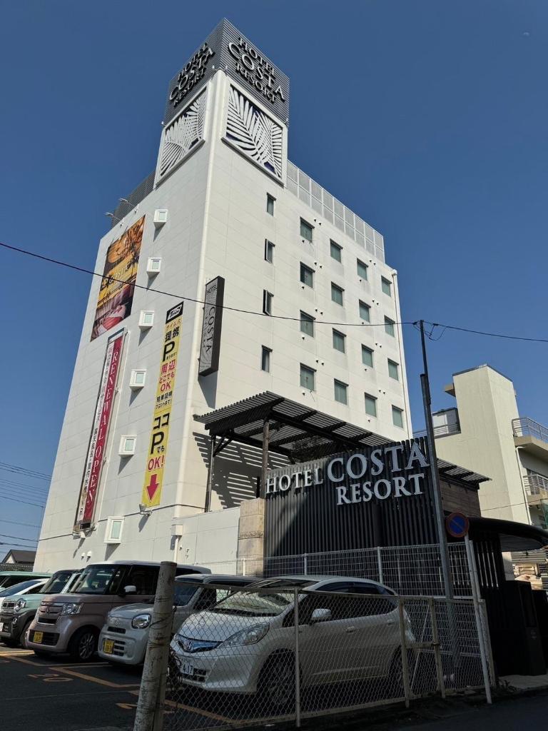 un hôtel avec des voitures garées devant lui dans l'établissement ホテルコスタリゾート飯能, à Hannō